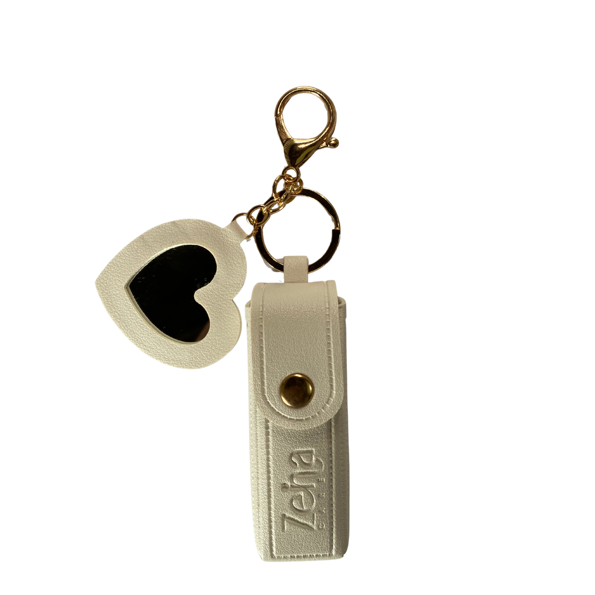 An off-white faux leather keychain set featuring a vertical sleeve with the brand name 'Zeina Care' embossed on it, a gold-tone snap button, and a matching off-white heart-shaped charm with a black center, all attached to a gold clasp on a plain white background.
